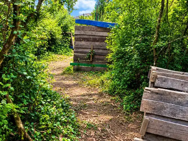 Cancha Bosque 1 de Quito Woodsball: sendero de tierra entre árboles y vegetación con barricadas de madera