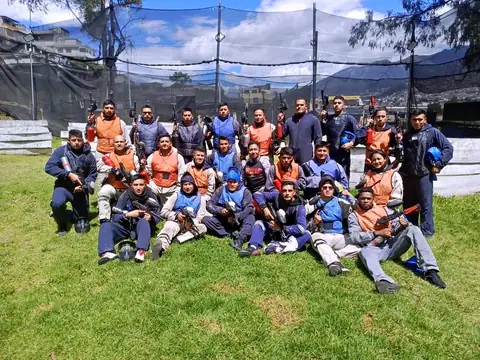 Grupo grande listo para jugar paintball en la cancha con vista a las montañas de Quito