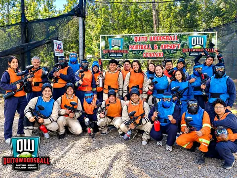 Equipo empresarial con chalecos naranja y azul frente al letrero de Quito Woodsball